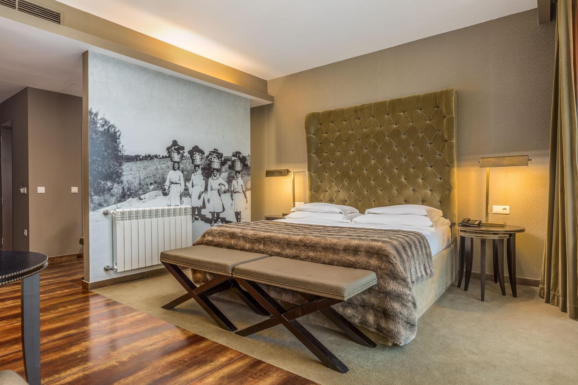 Ap Lago Montargil - Conference & Spa Zewnętrze zdjęcie The photo shows a modern hotel room with a large, plush bed that has a tufted, green headboard. The bedding is white with a textured blanket at the foot of the bed. A decorative wall behind the bed features a black and white mural of children in a fi