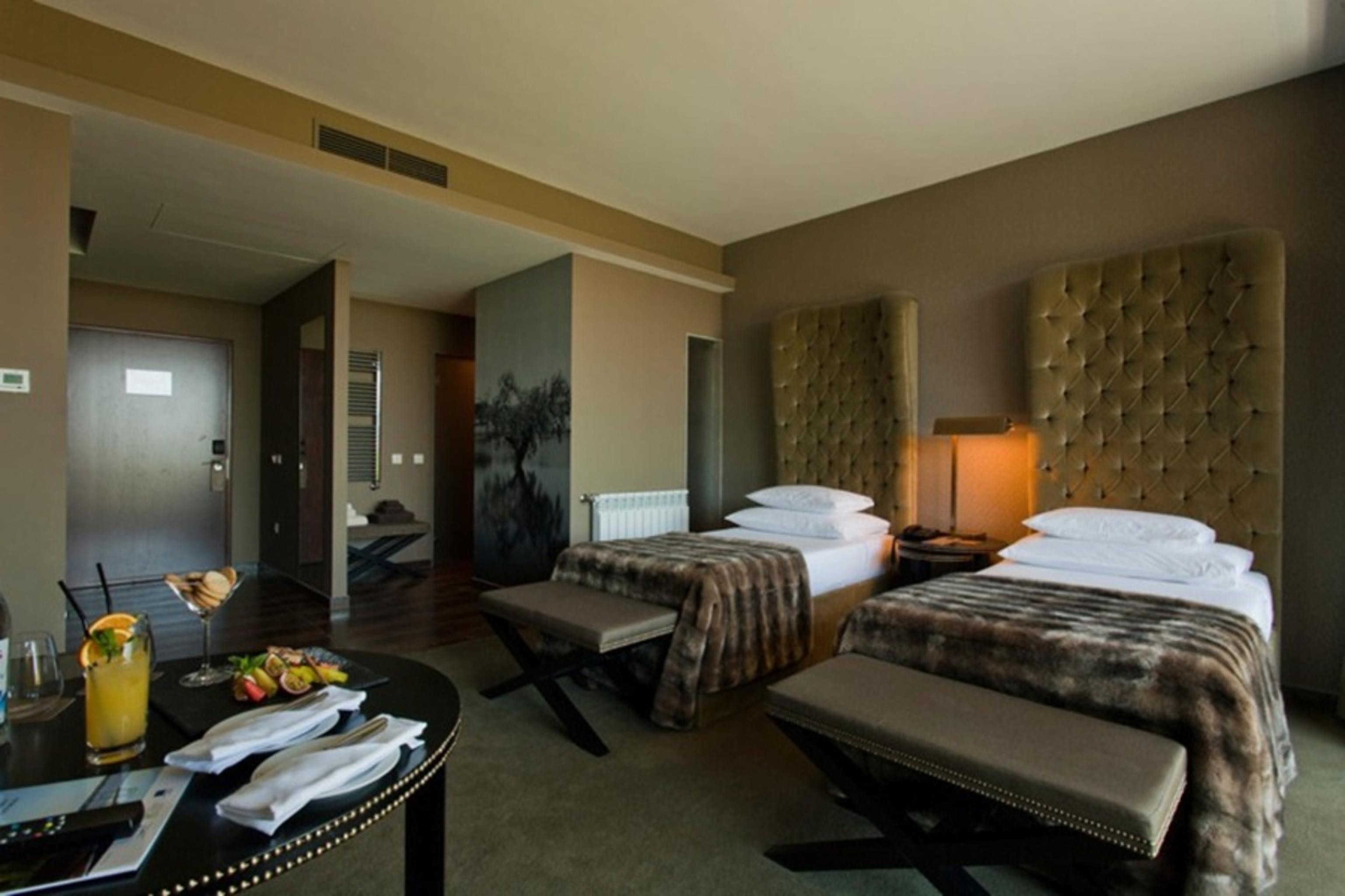 Ap Lago Montargil - Conference & Spa Zewnętrze zdjęcie The photo shows a stylish hotel room featuring two beds with plush, upholstered headboards. The room has a modern and elegant design, with earthy tones dominating the decor. A small round table is set up in the foreground, displaying a drink and some